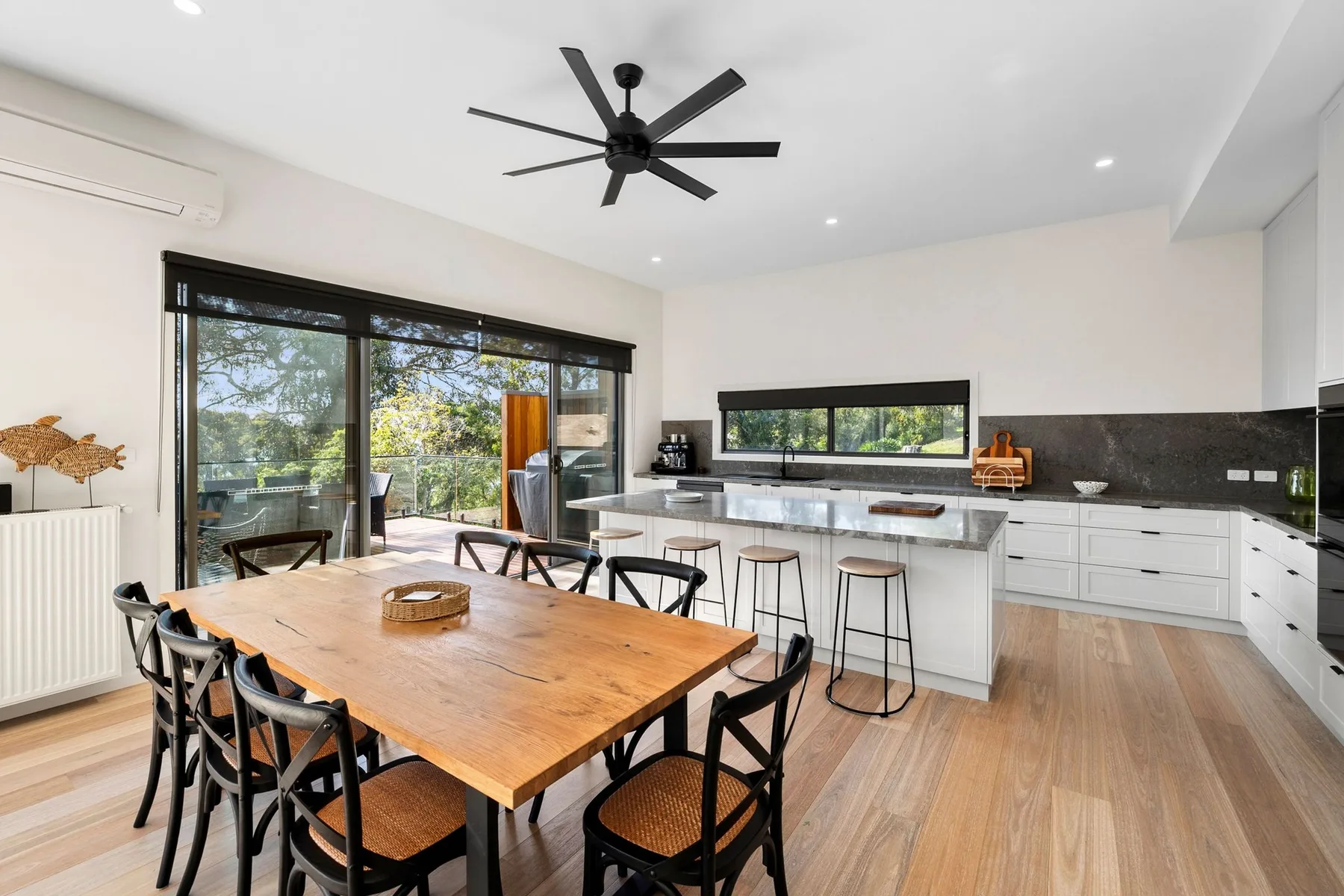 Una cocina y comedor luminosos con una mesa de madera y asientos junto a la encimera.
