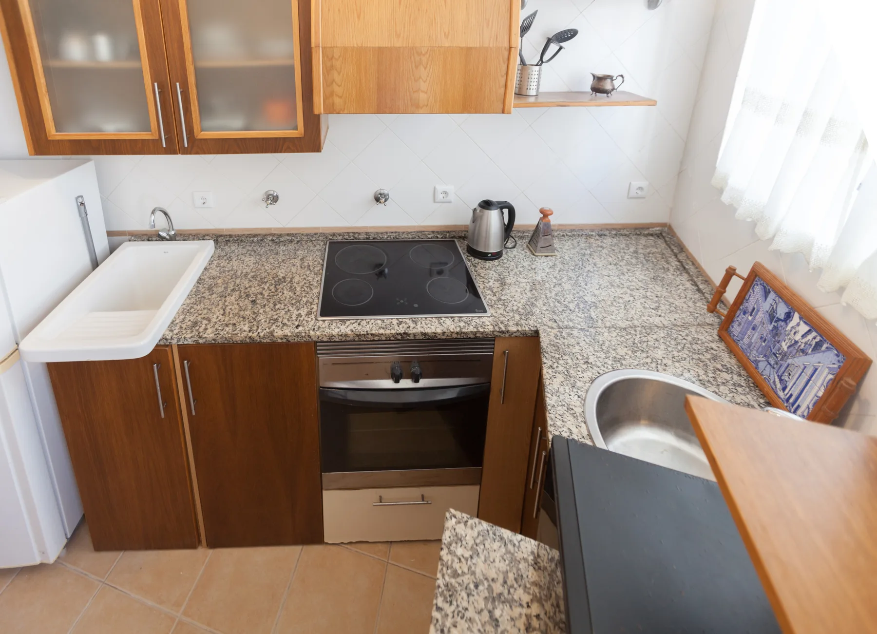 Una cocina compacta con armarios de madera, una placa de cocina y un fregadero sobre la encimera.