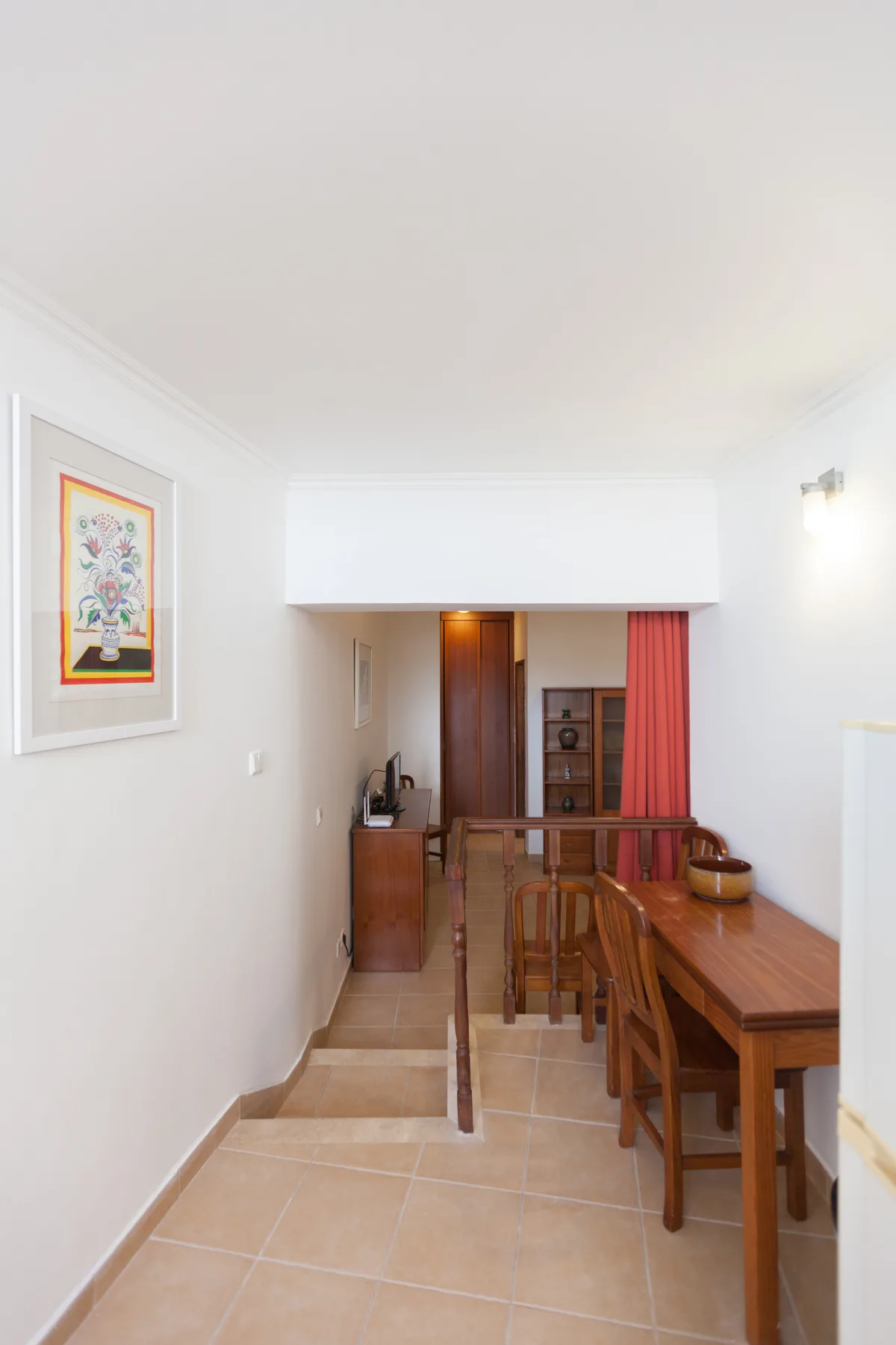 A narrow dining area with a long wooden table and chairs.
