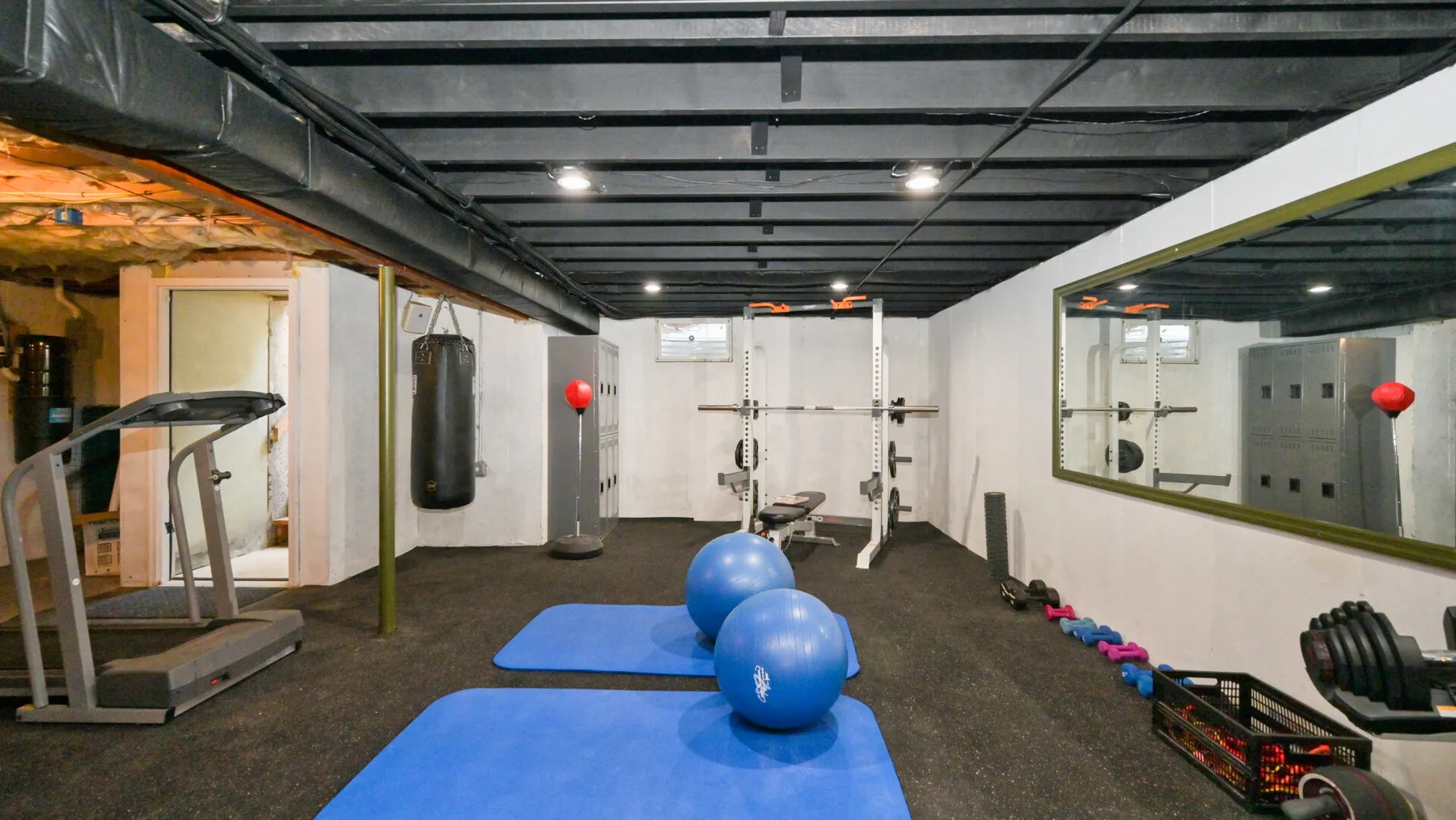 Un gimnasio con colchonetas, pesas y una cinta de correr.