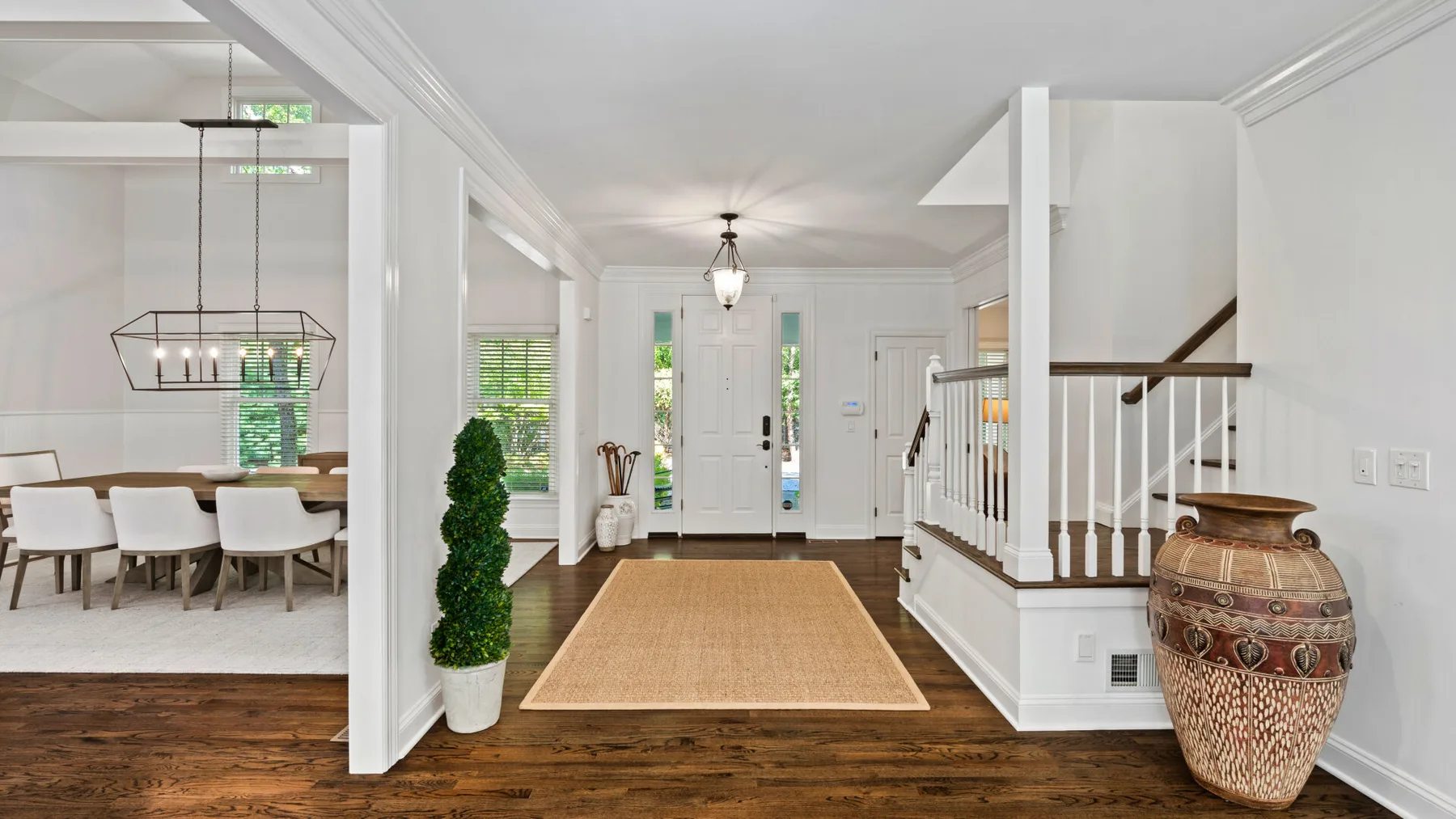 Una luminosa entrada con suelo de madera, alfombra y escalera.
