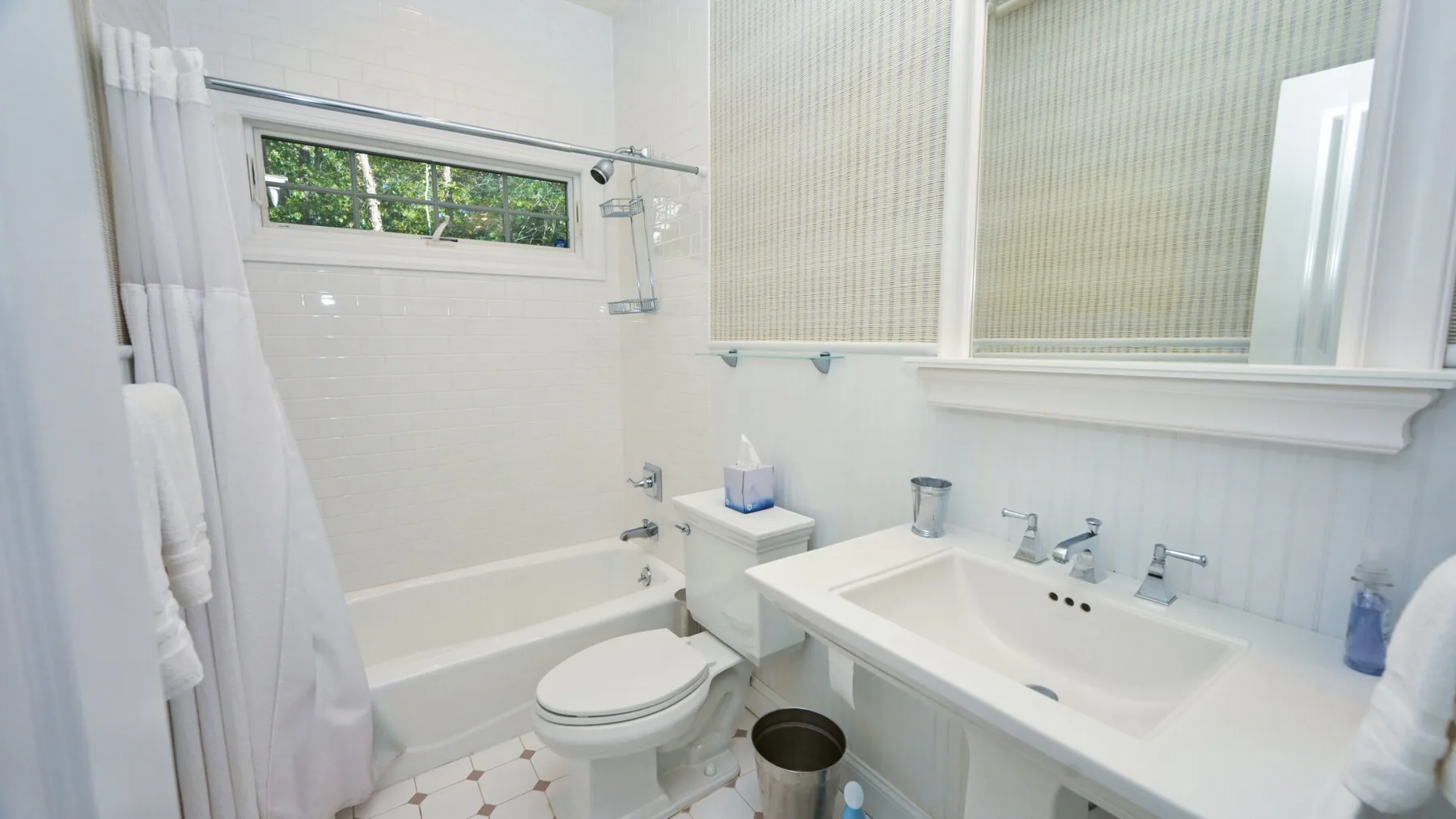 Un baño luminoso con bañera, inodoro y lavabo bajo un espejo grande.