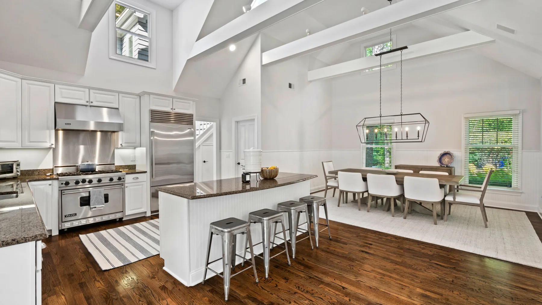 Una luminosa cocina abierta con comedor, isla central y mesa.