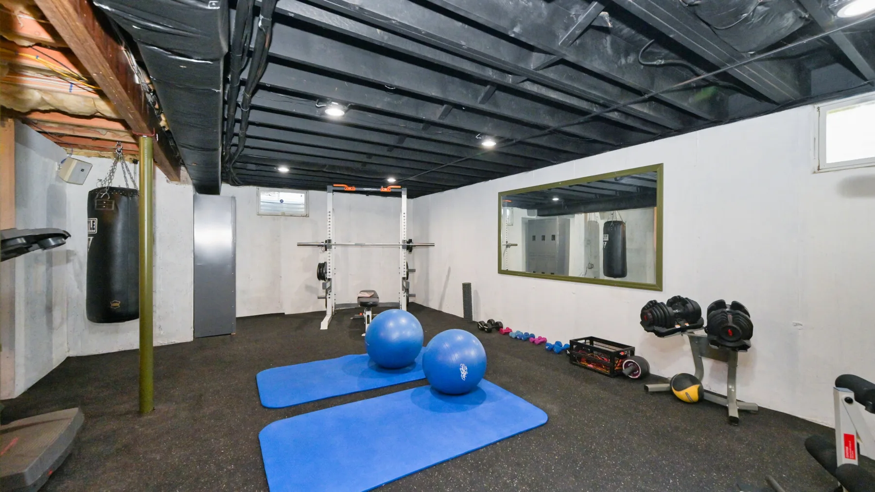 Un gimnasio con colchonetas azules, pesas y equipo para hacer ejercicio.