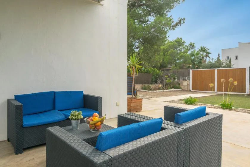 An outdoor patio has dark woven seating with bright blue cushions beside a small table.
