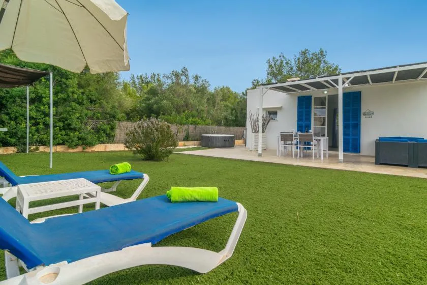A sunny outdoor lawn with blue loungers and a covered patio.