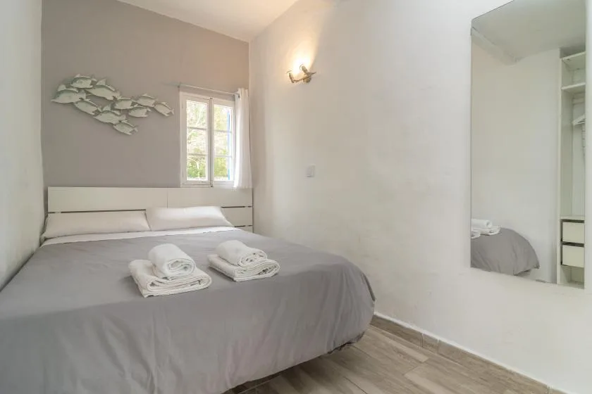 A bedroom with a large bed, folded towels, and a window.