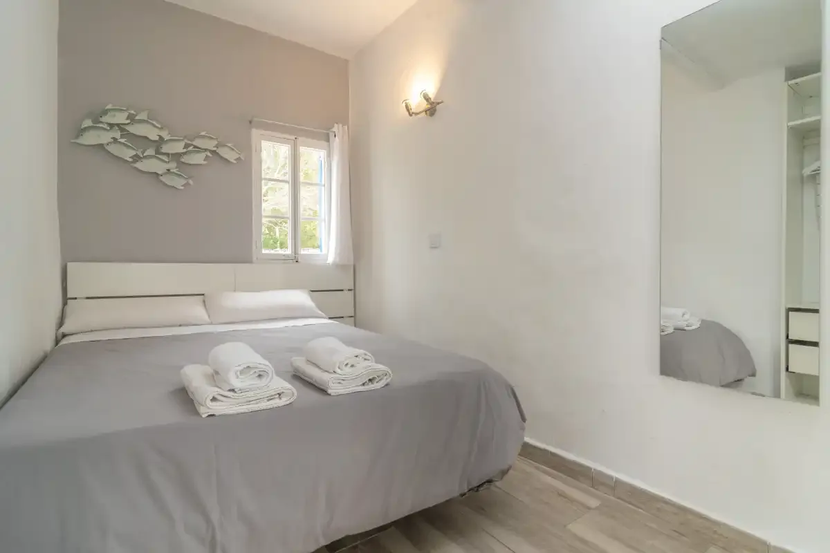 A bedroom with a neatly made bed and a window.