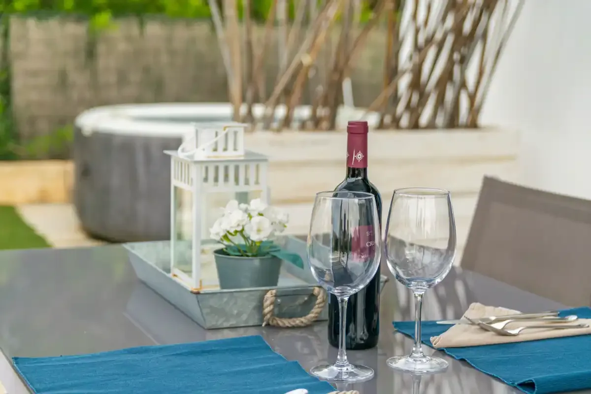 A dining table is set with wine glasses, a bottle, and blue napkins.