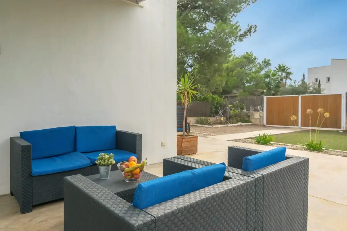 Outdoor patio seating with blue cushions overlooks a paved garden area.