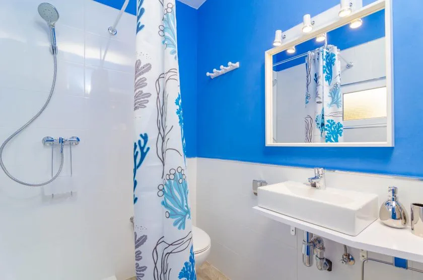 A bright bathroom with a sink, mirror, and patterned shower curtain.
