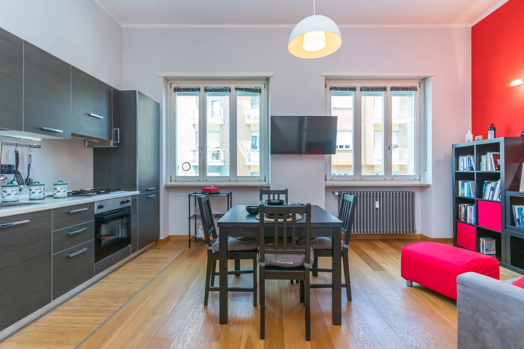 Comedor con mesa y sillas junto a la cocina y ventanas luminosas.
