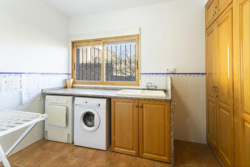 Un cuarto de lavado con una lavadora y una ventana sobre la encimera.