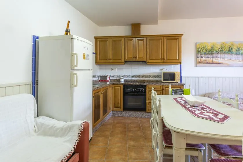 Una cocina y comedor con gabinetes de madera, un refrigerador y una mesa.
