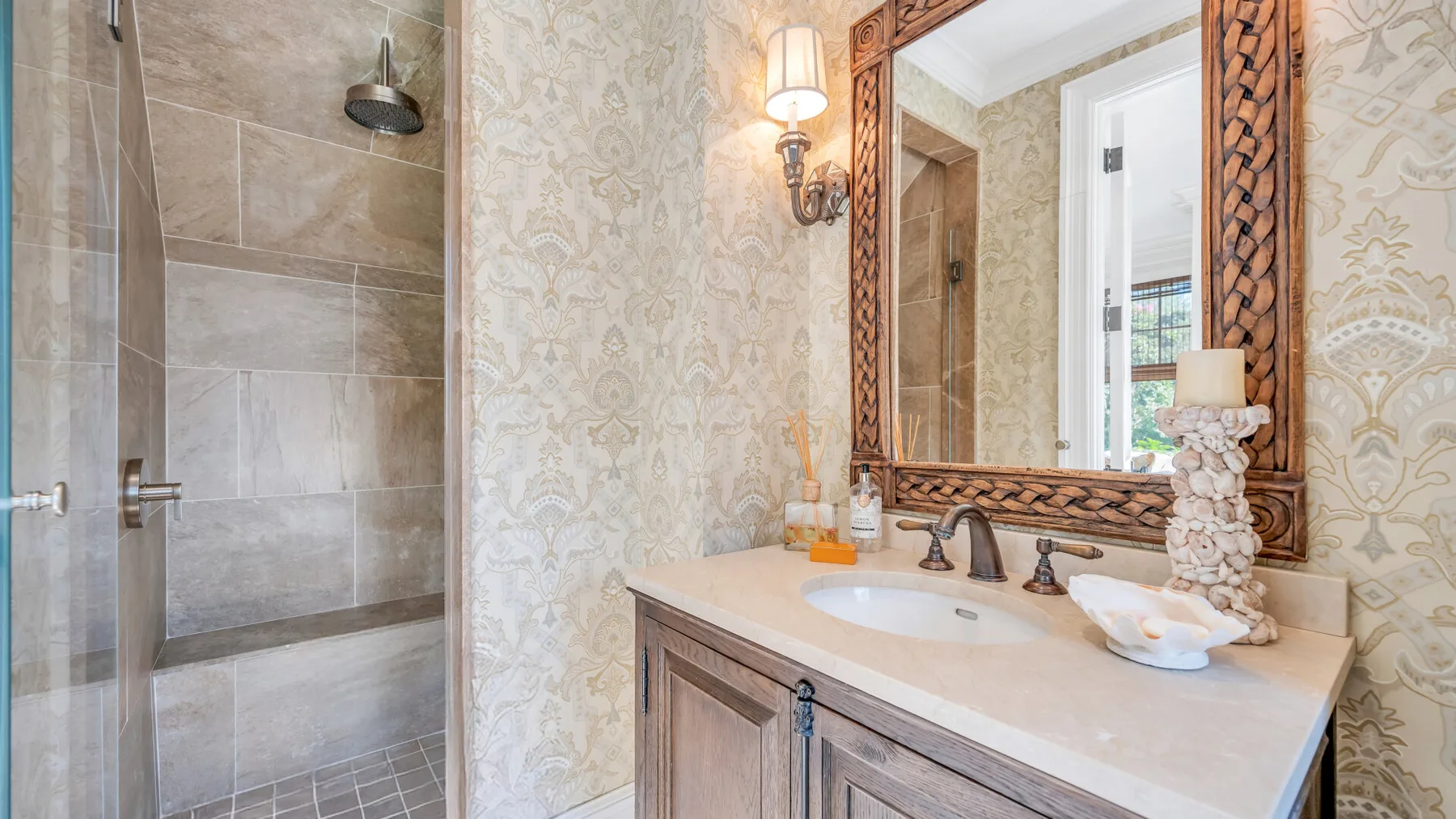 Un tocador de baño con lavabo y espejo junto a una ducha de vidrio.