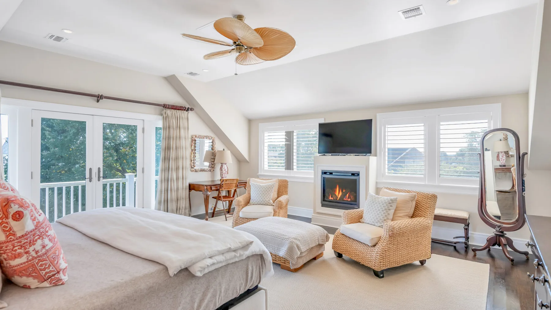 Un dormitorio luminoso con cama, chimenea y asientos junto a grandes ventanas.