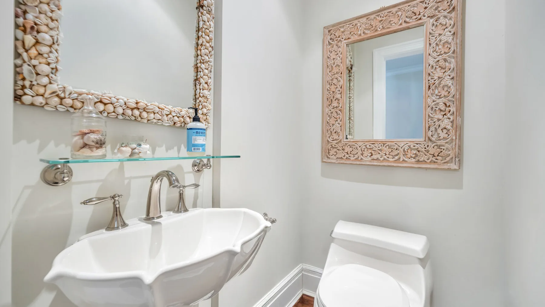 Un tocador de baño con un lavabo blanco y un espejo con marco ornamentado.