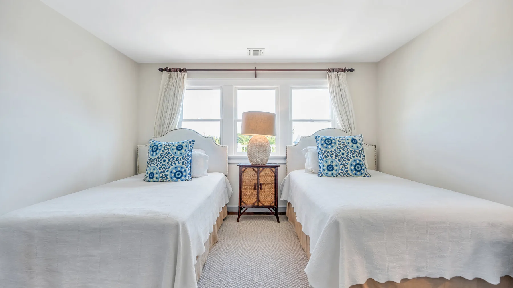 Un dormitorio luminoso con dos camas y una ventana entre ellas.