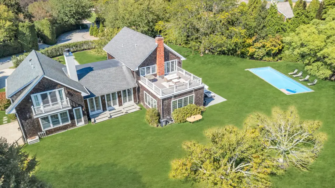 An aerial view shows a large house, lawn, and swimming pool.