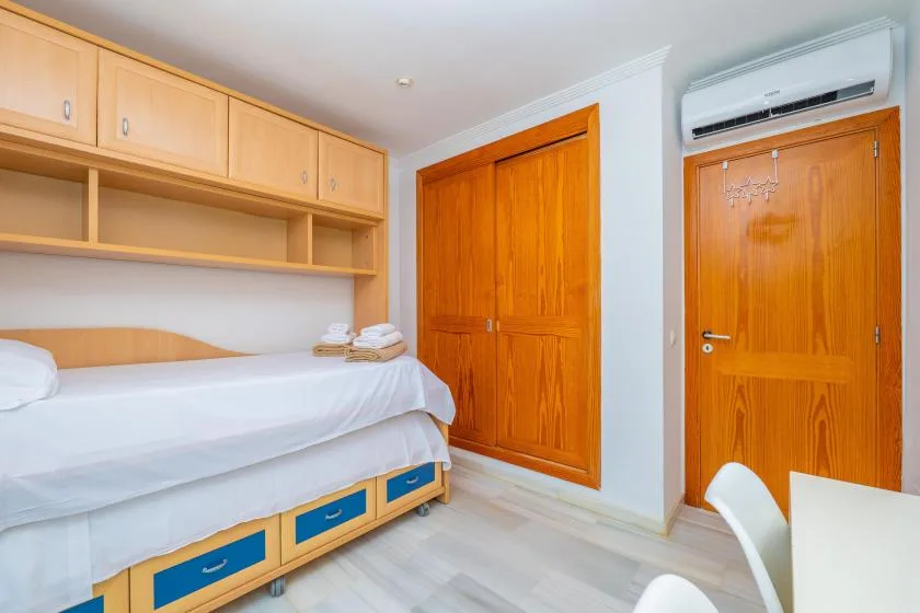 Un dormitorio con una cama individual, armarios empotrados y una puerta de madera.