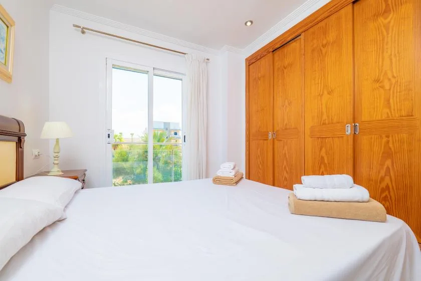 Un dormitorio luminoso con una cama bien tendida y armarios de madera.