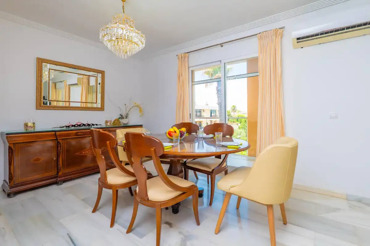 Comedor con una mesa, sillas y un aparador junto a una ventana.