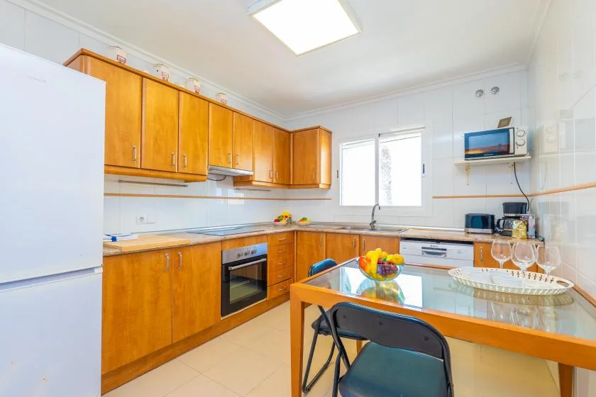 Una cocina luminosa con gabinetes de madera, una encimera y una mesa de comedor.