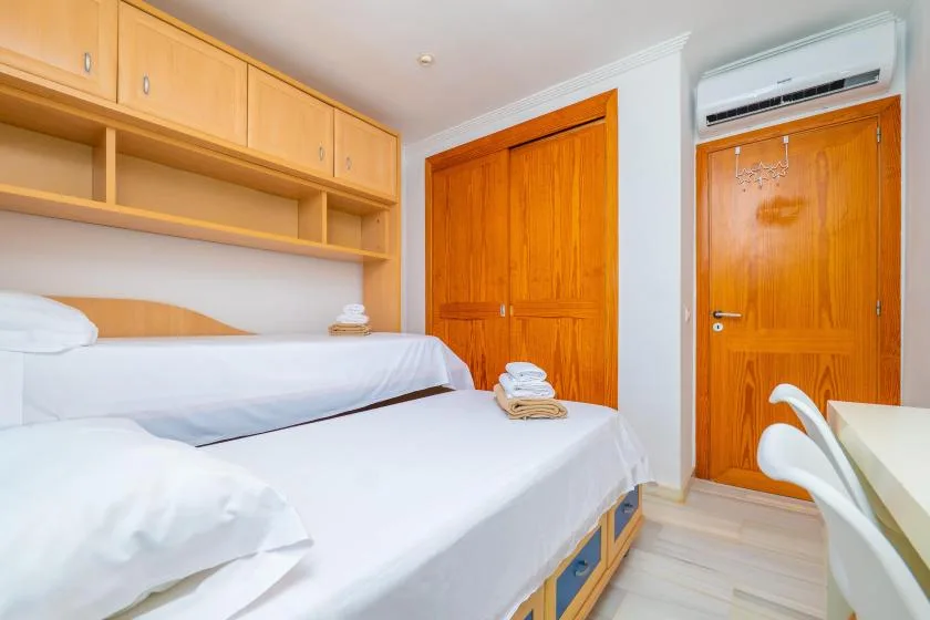 Un dormitorio con dos camas, armarios de madera y una puerta de madera.