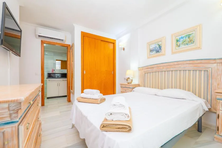 Dormitorio con una cama hecha y un armario de madera junto a la puerta.