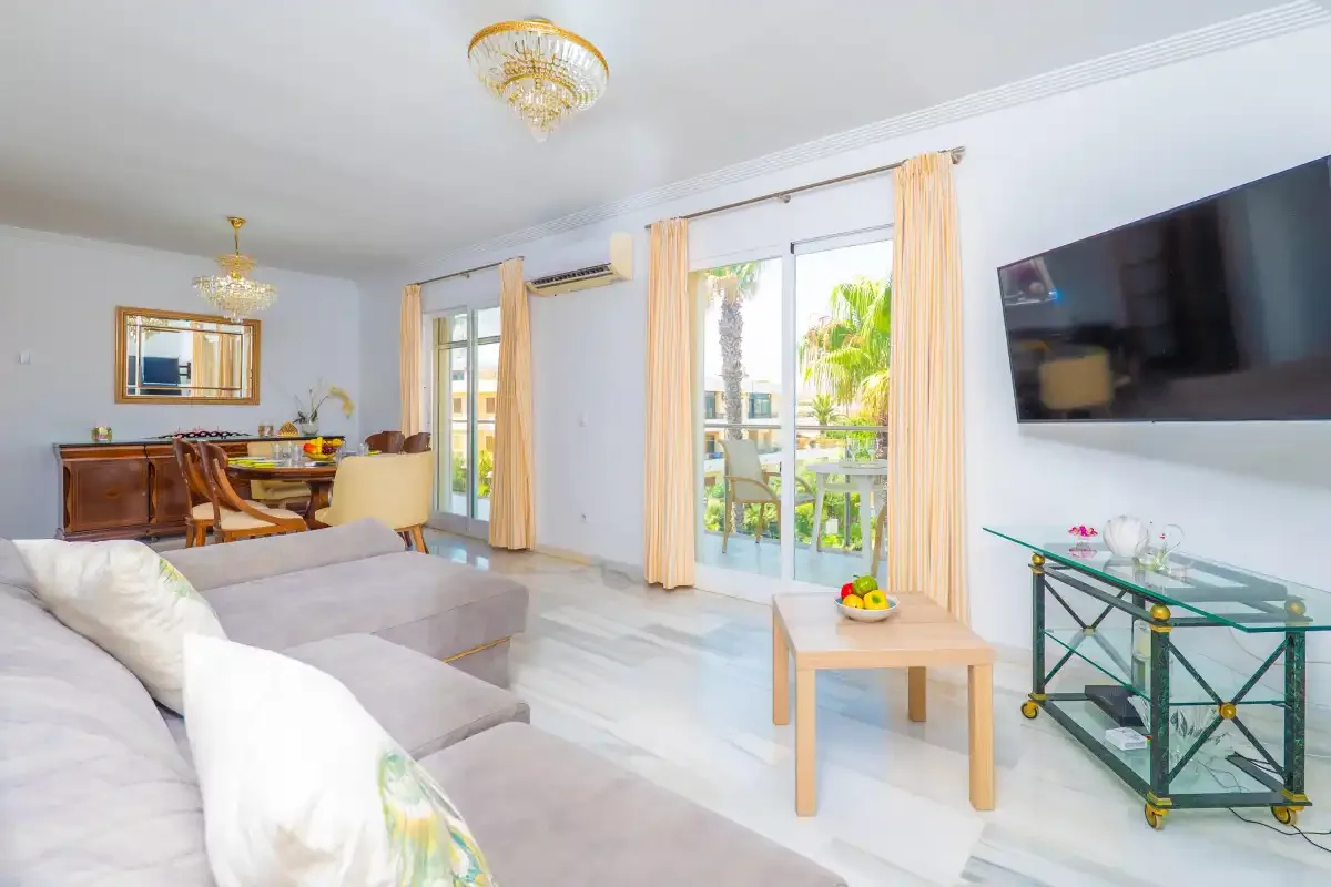 Una sala luminosa con asientos, un comedor y puertas de cristal que dan a un balcón.