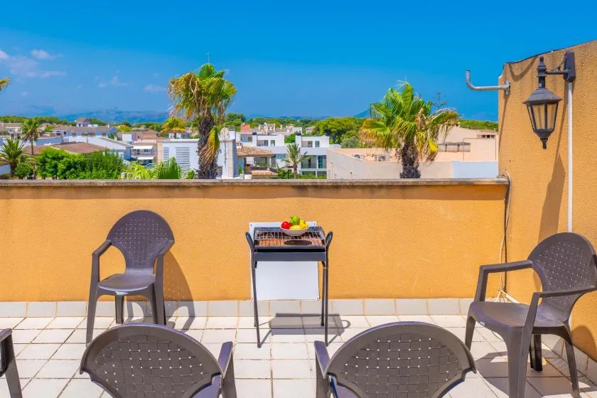 Una terraza soleada en la azotea con asientos al aire libre y vistas a edificios cercanos.