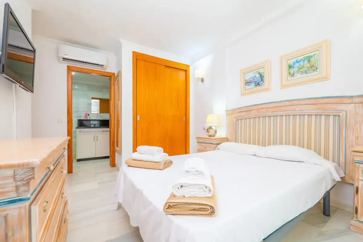 Un dormitorio luminoso con una cama bien hecha y una puerta de madera.