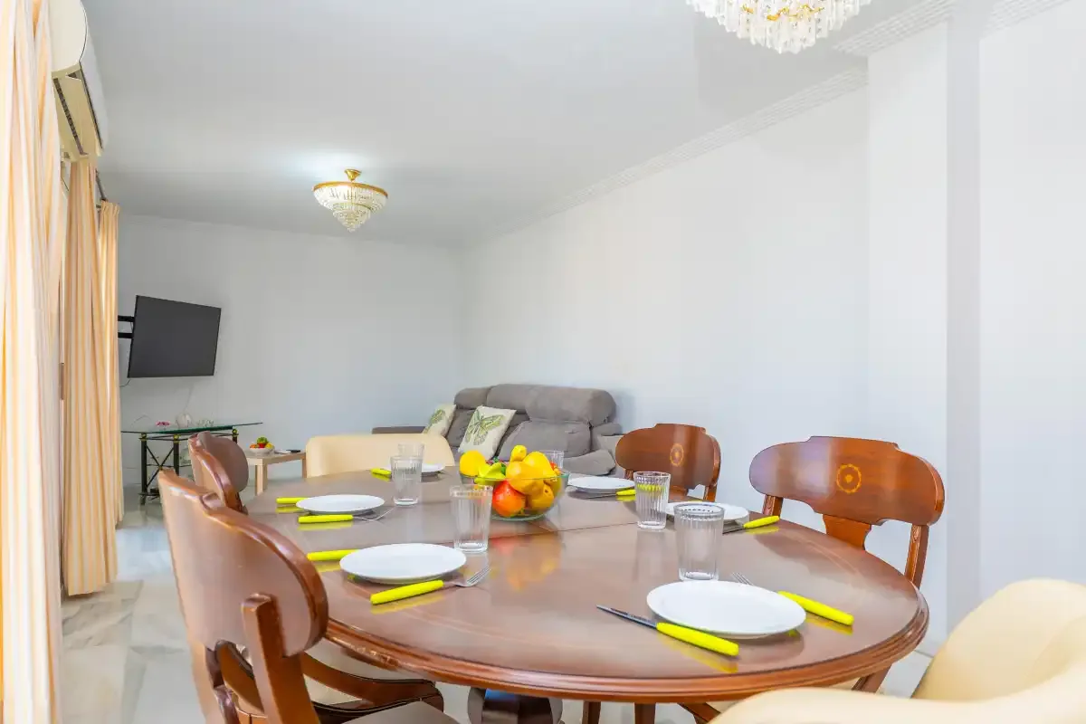 Comedor con la mesa puesta y asientos, junto a una zona de estar.