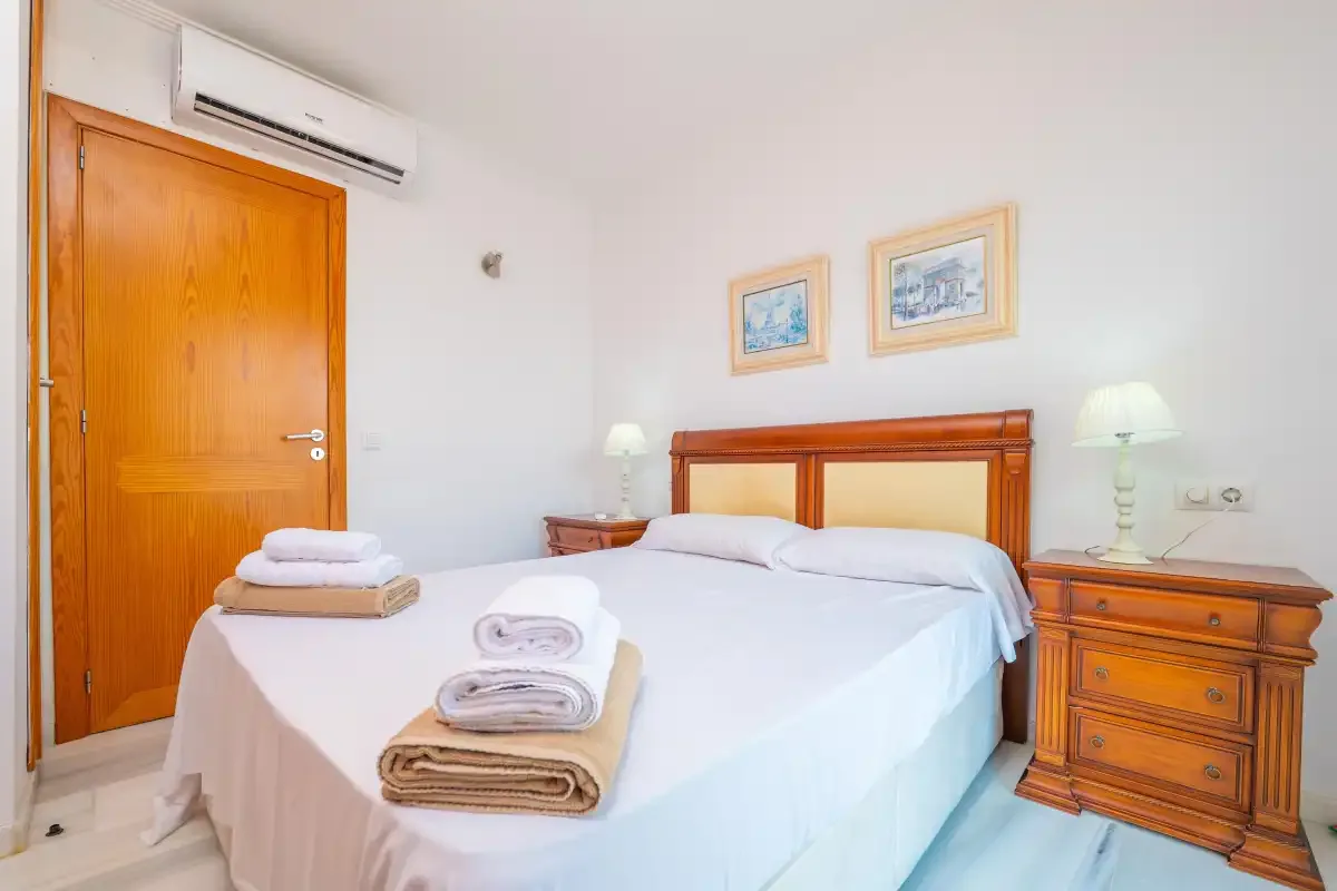 Un dormitorio con una cama bien hecha y mesitas de noche de madera a juego.