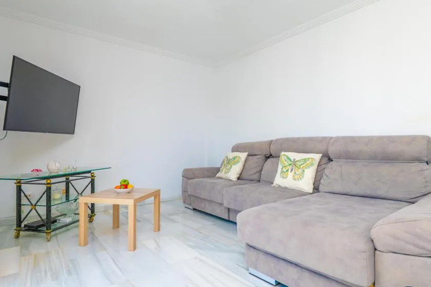 A living room with a sectional sofa, a glass TV stand, and a small coffee table.