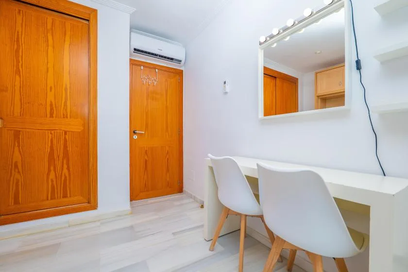 Un vestidor luminoso con tocador blanco, espejo y asientos.