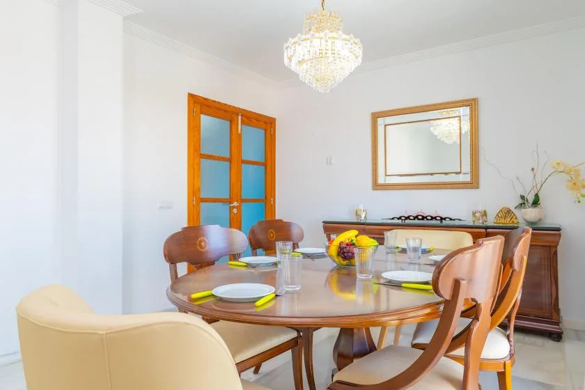 Un comedor luminoso con una mesa puesta y una lámpara de araña.