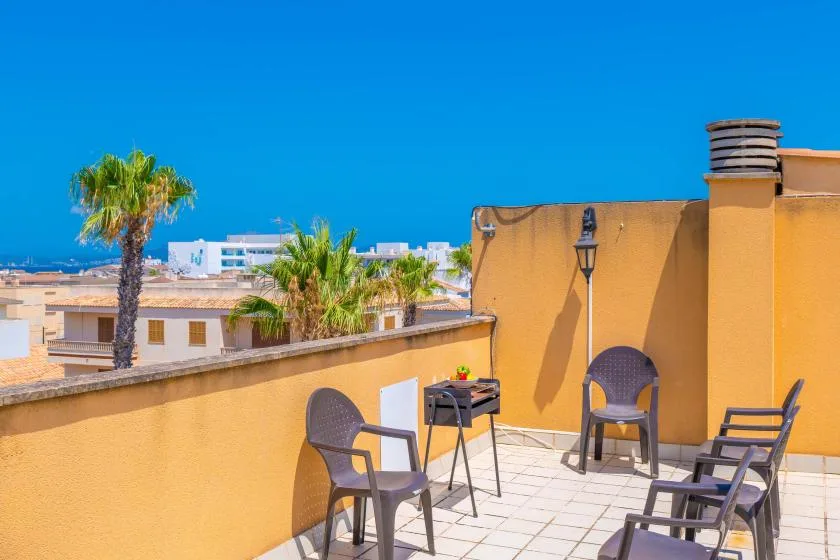 Una terraza soleada en la azotea con asientos al aire libre y vistas a edificios cercanos.