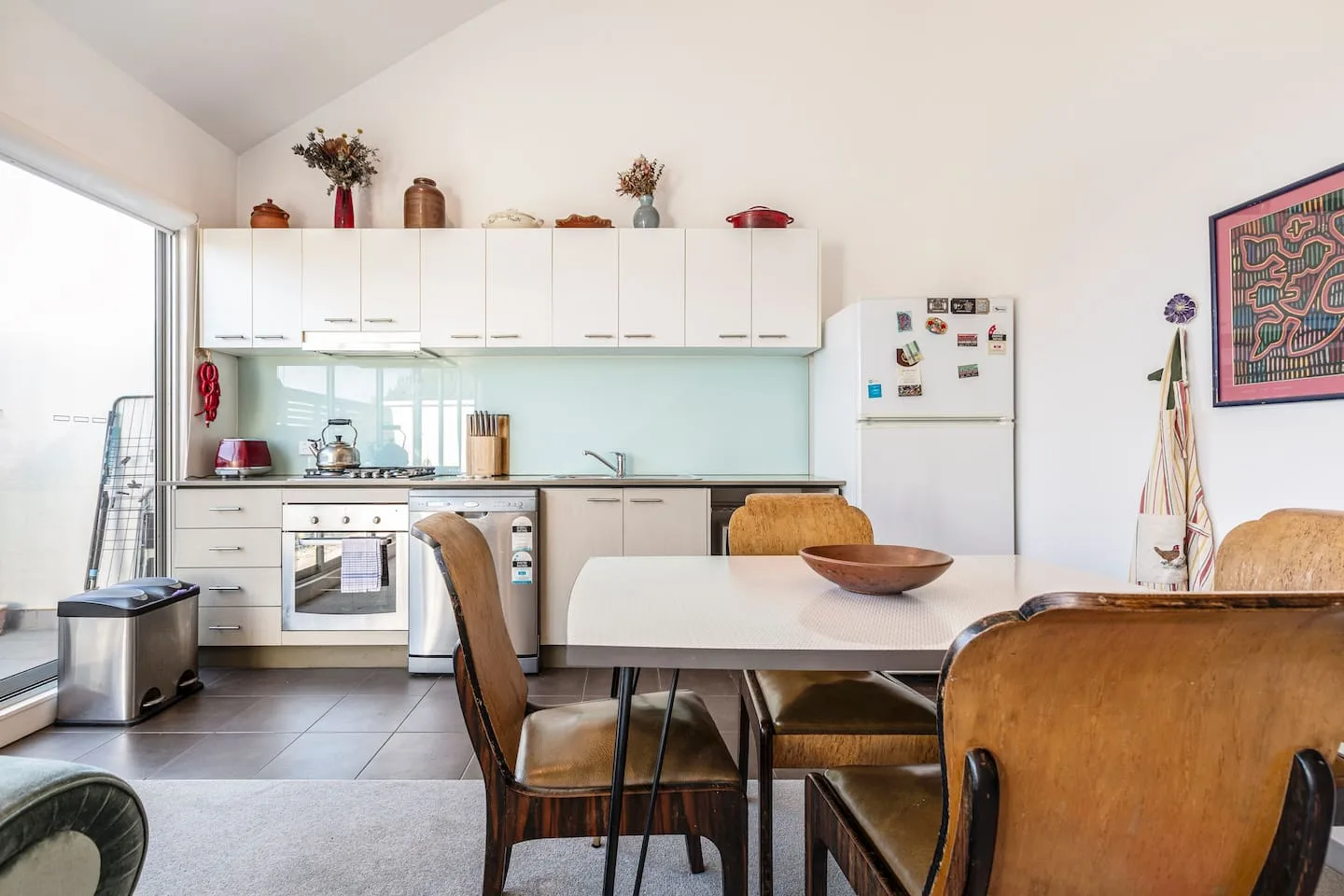 A bright kitchen and dining area with white cabinetry and a dining table.