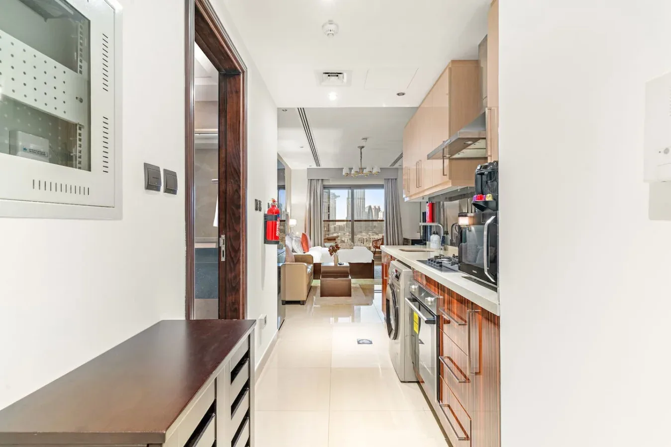 Una cocina se abre a una sala de estar con asientos y ventanas grandes.