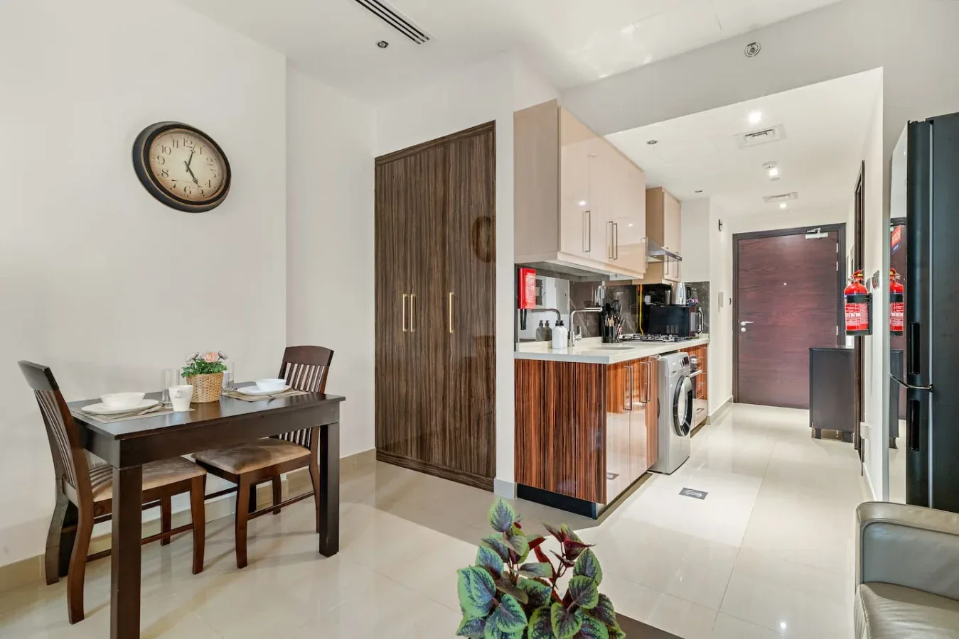 Un comedor y una cocina compacta están junto a un pasillo que lleva a una puerta cerrada.