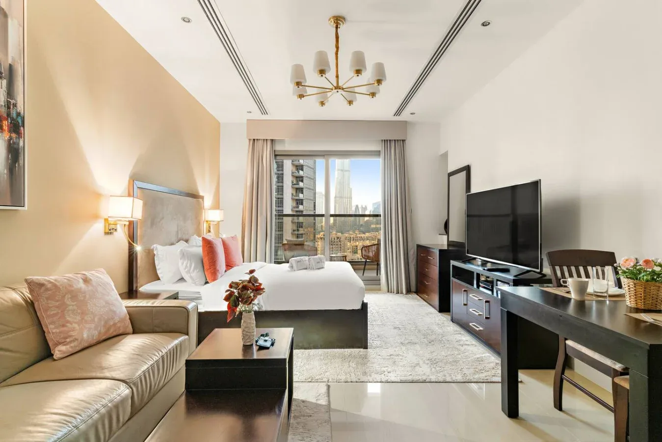 Un estudio con dormitorio y sala de estar se abre a un balcón con edificios altos cercanos.