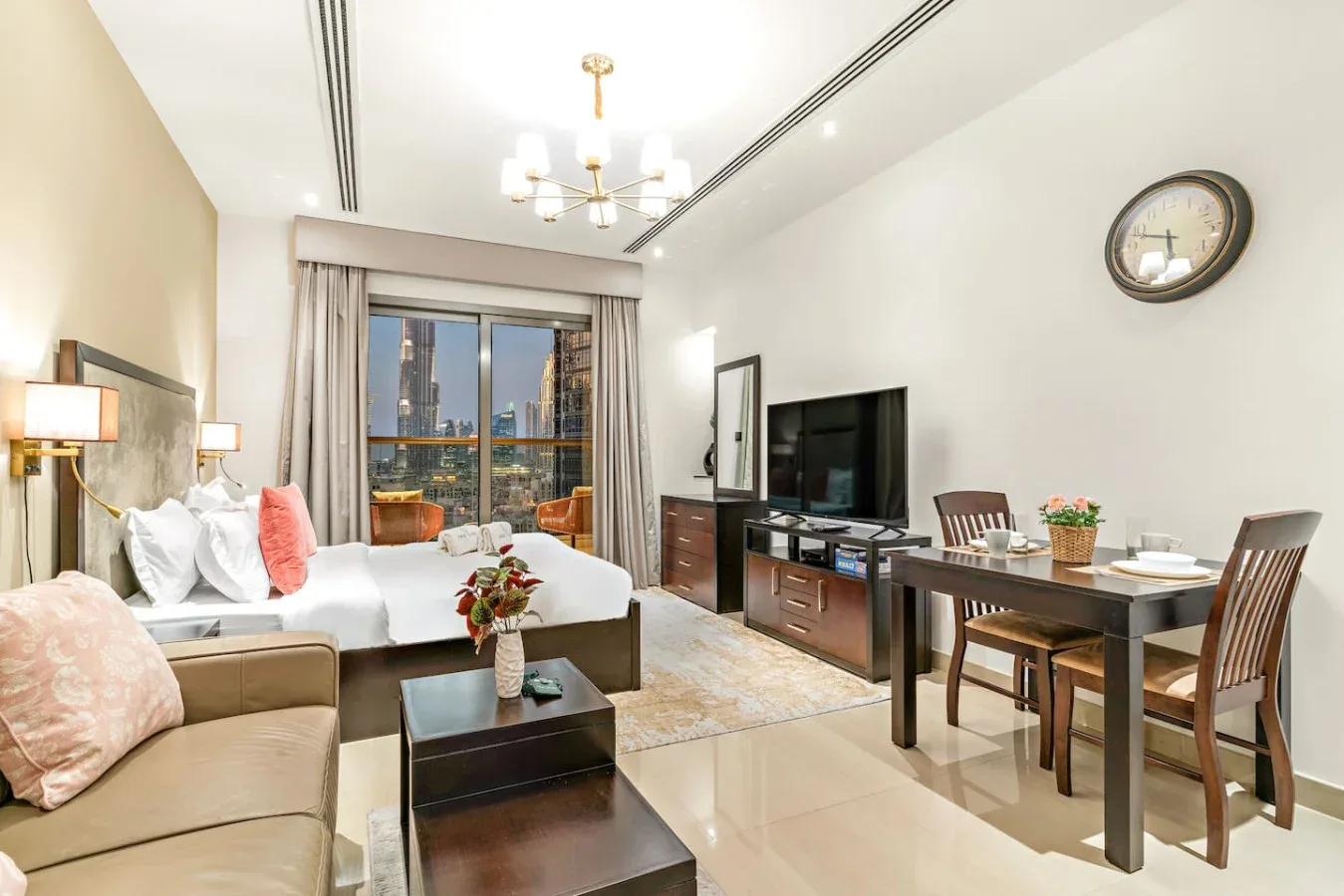 Una sala de estudio amueblada con cama, asientos, mesa de comedor y televisor.