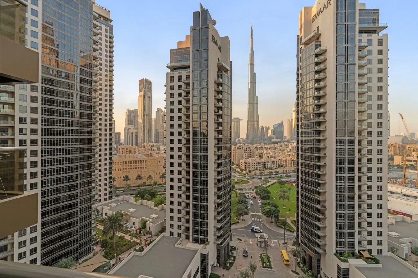 A city skyline framed by tall high-rise buildings, with roads and greenery below.
