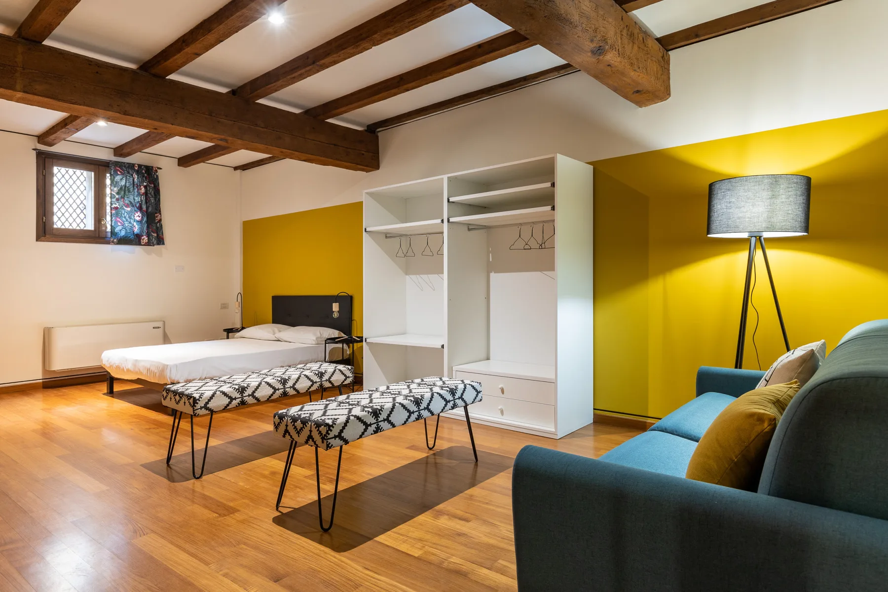 Dormitorio y zona de estar con camas, un sofá y armarios abiertos.