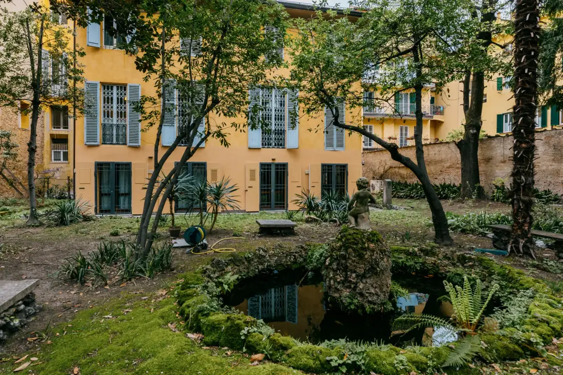 Un jardín de patio con un estanque pequeño y árboles frondosos.
