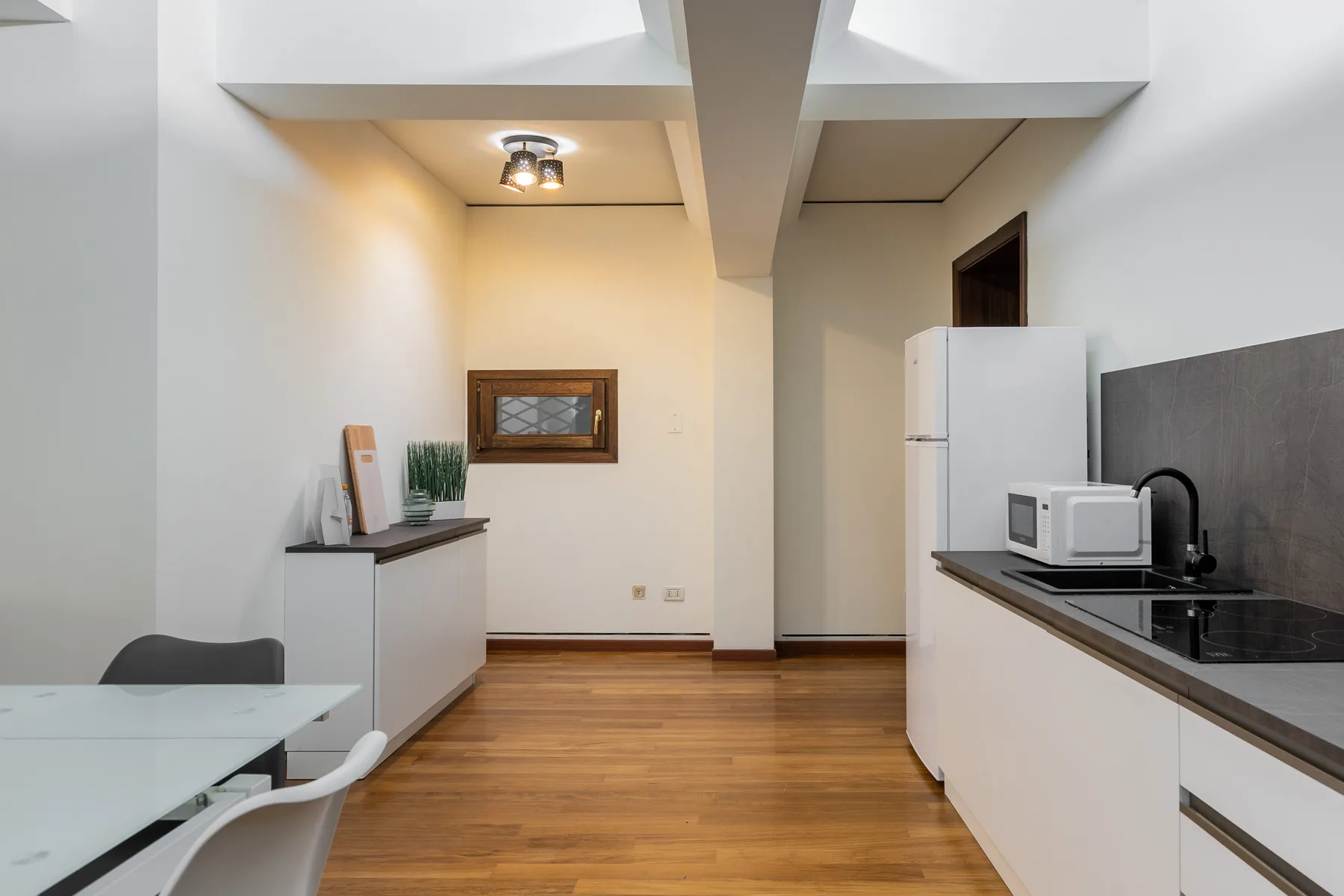 Cocina y comedor con suelo de madera, una encimera y un refrigerador.