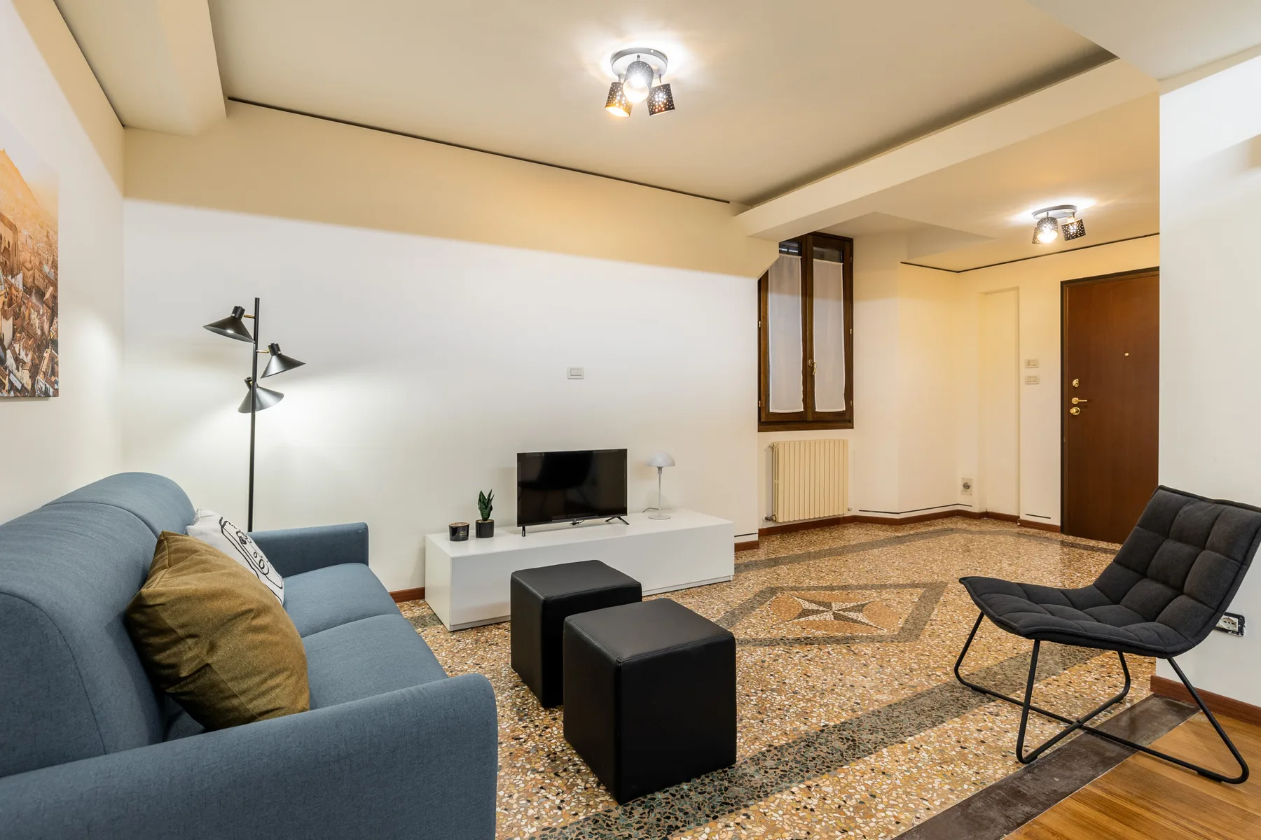 Una sala de estar con asientos, un televisor y un suelo estampado.