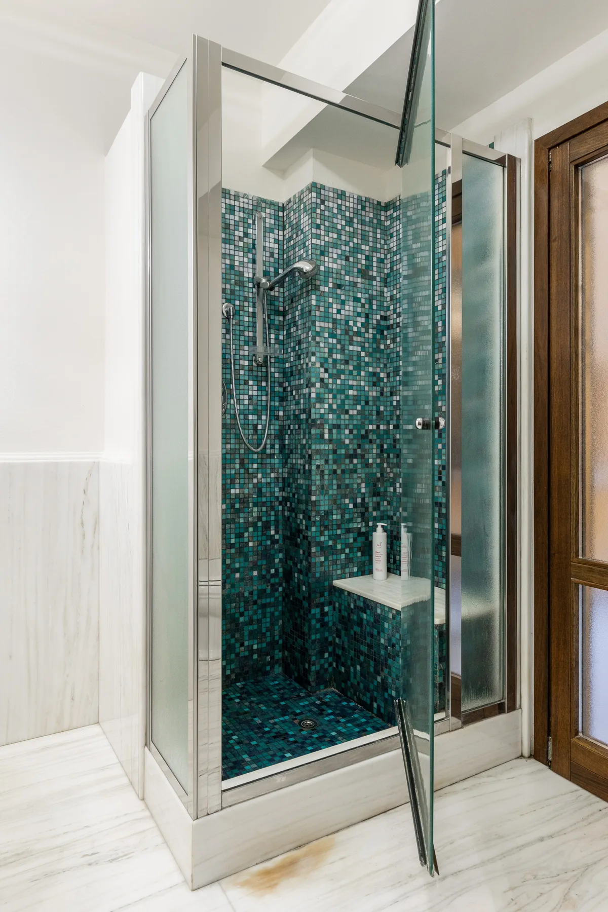 Una ducha de baño con azulejos, paneles de vidrio y un cabezal de ducha en la pared.