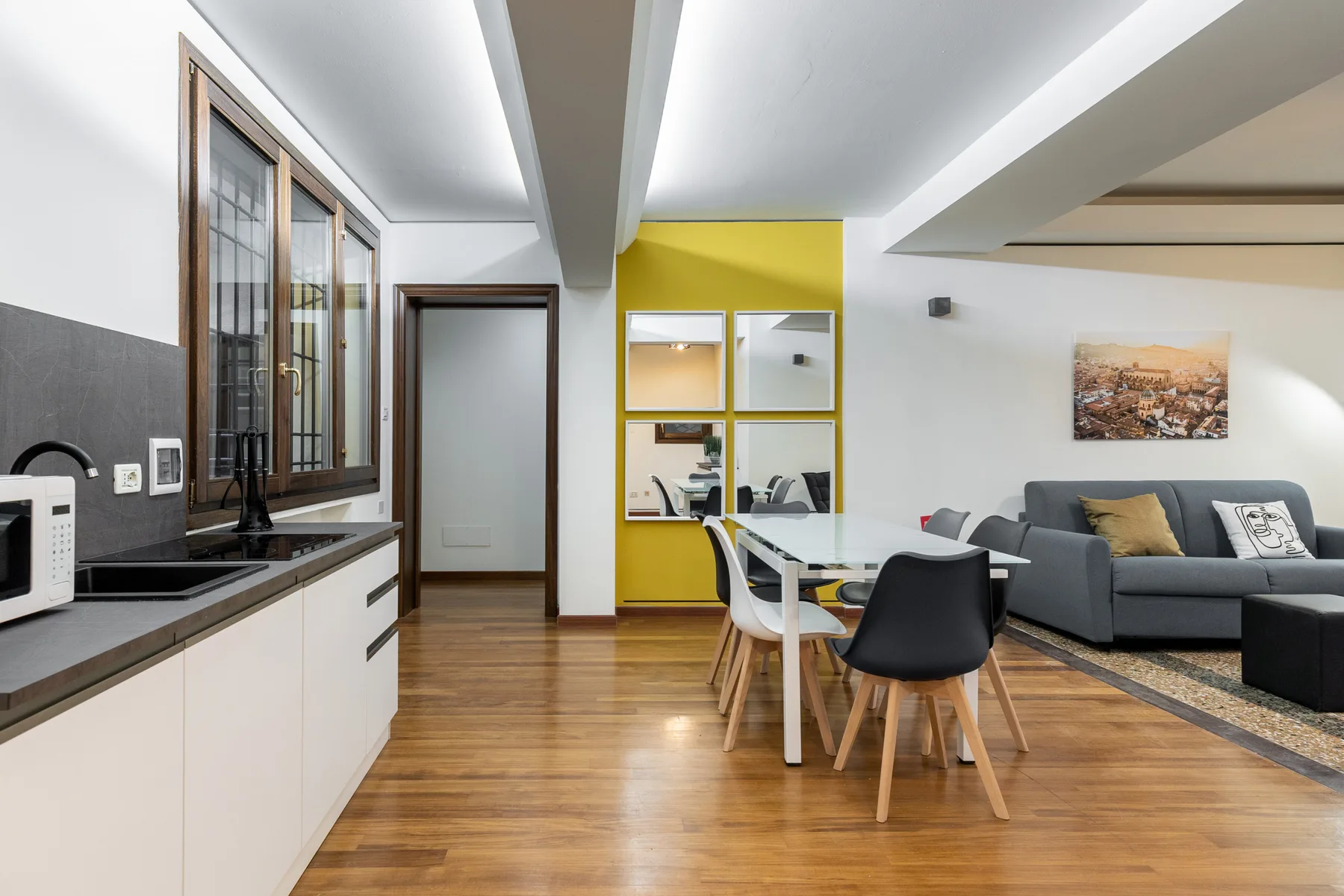 Una sala de estar y comedor diáfana con una encimera de cocina y asientos grises.